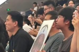 詹姆斯中國(guó)行成都活動(dòng)現(xiàn)場(chǎng) 一球迷拿著詹姆斯經(jīng)典哭臉照坐在場(chǎng)邊